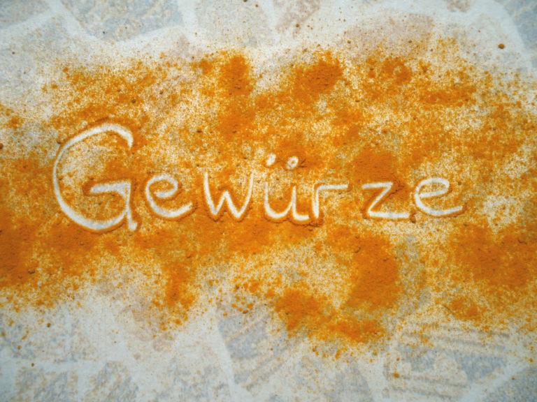 "Gewürze" mit dem Finger geschrieben in Gwürzen auf einem Tisch